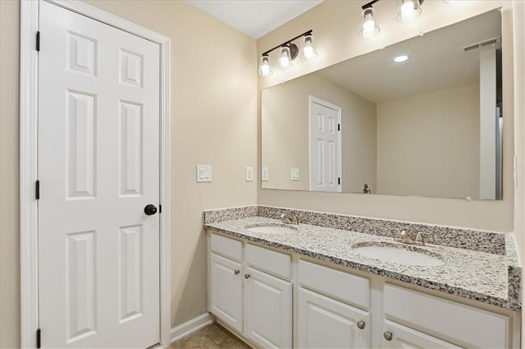 5630 Lawley Road Alpharetta, GA 30022 - Photo 44 of 65 a bathroom with a granite countertop sink and white cabinets