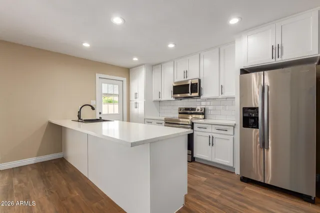 a kitchen with white cabinets and stainless steel appliances