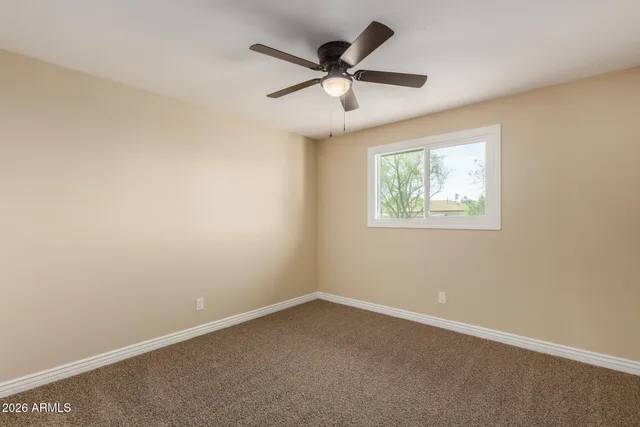 an empty room with a window and a ceiling fan