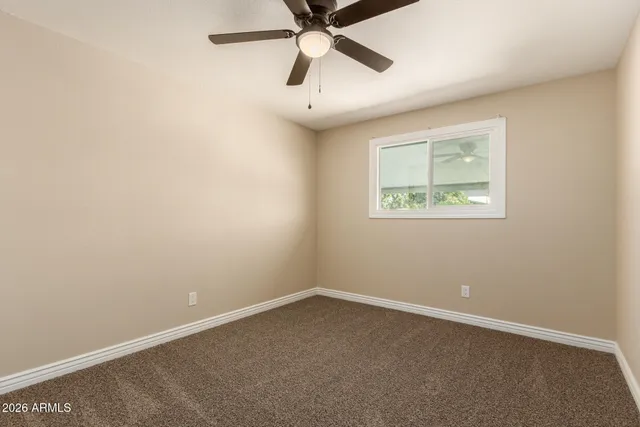 an empty room with a window and a fan