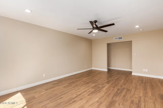 an empty room with wooden floor and a ceiling fan