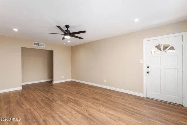an empty room with wooden floor and a ceiling fan