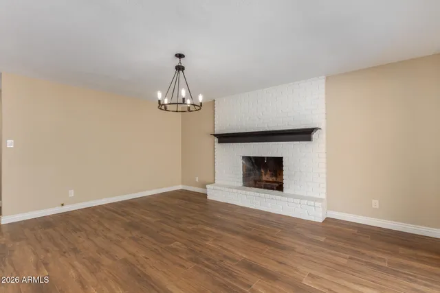 a view of an empty room with wooden floor fireplace and a window