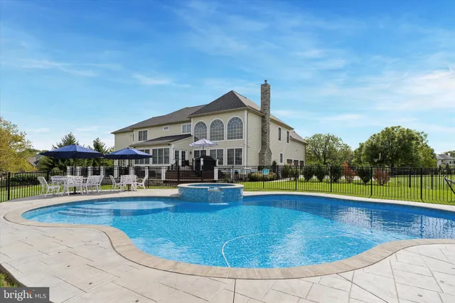 a view of pool with lawn chairs and large trees