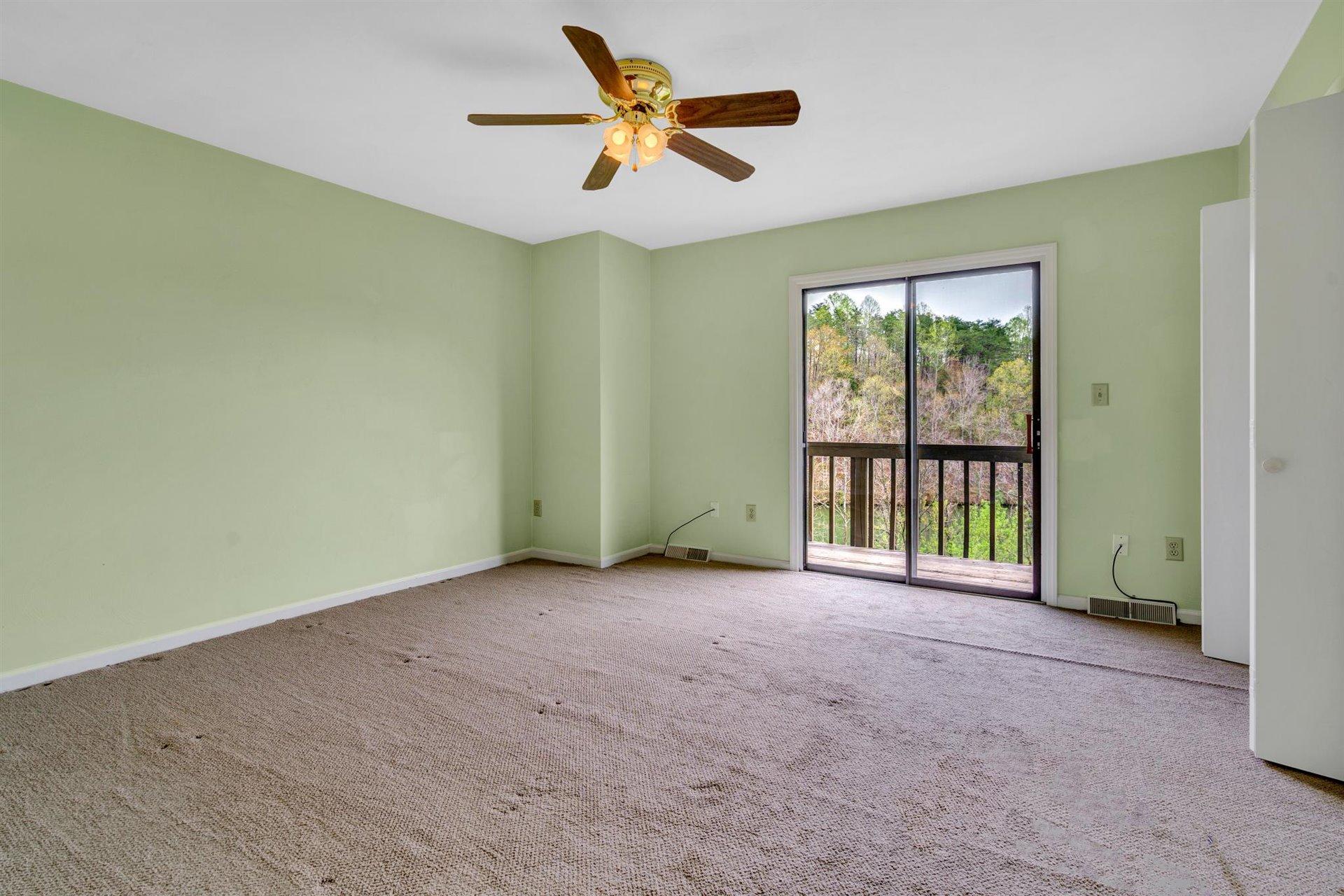 202 Harbor Ridge Drive Goodview, VA 24095 - Photo 14 of 30 an empty room with a ceiling fan and a floor to ceiling window