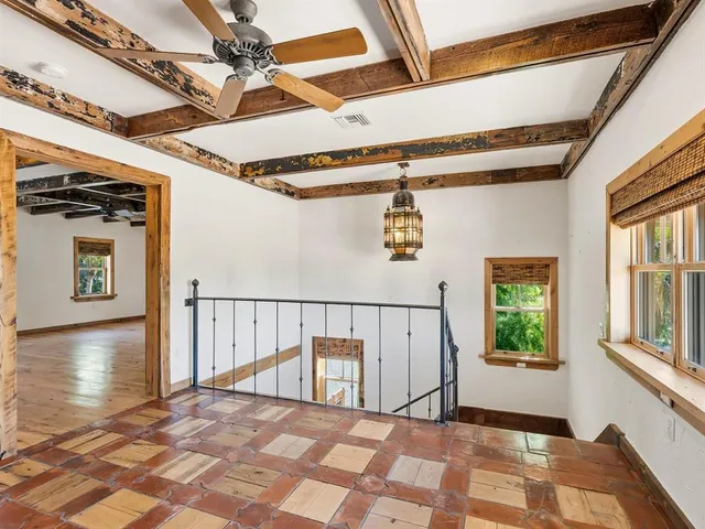 a view of a hallway with wooden floor and windows