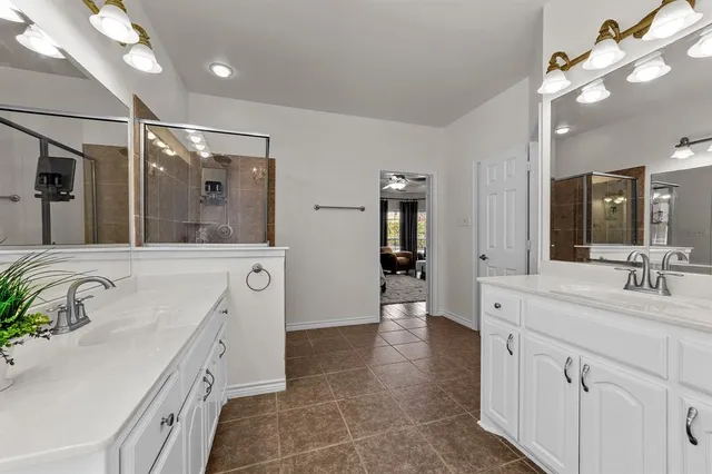 a spacious en suite bathroom with a double vanity sink a mirror and shower