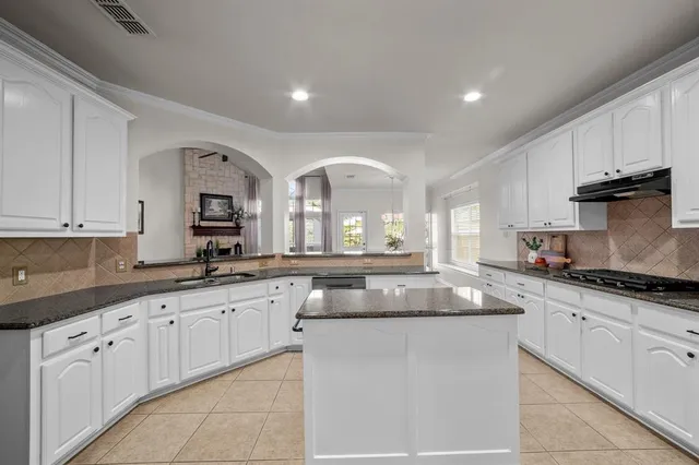 a kitchen with granite countertop a sink white cabinets and stainless steel appliances