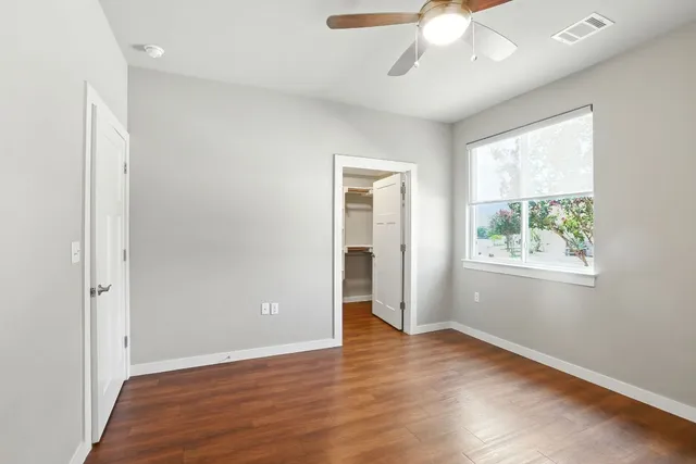 a view of an empty room with wooden floor and a window