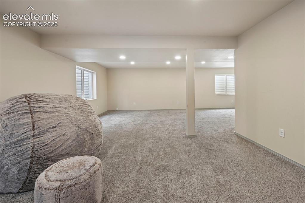 8347 Tibbs Road Peyton, CO 80831 - Photo 9 of 39 Spacious room featuring neutral paint, gray carpeting, recessed lighting, and white window shutters