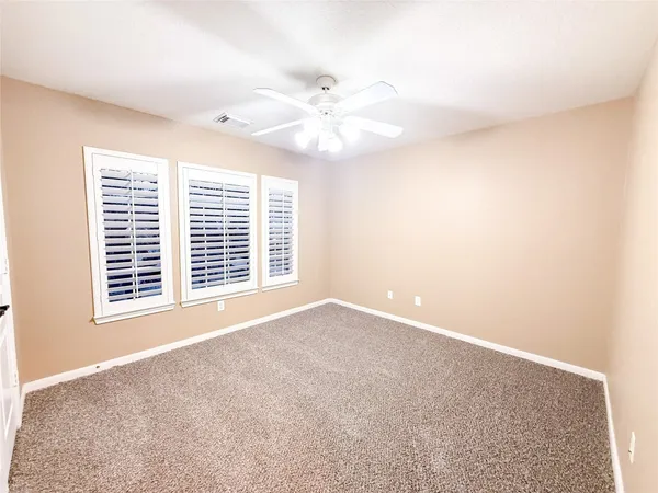 a view of an empty room with a window and a ceiling fan