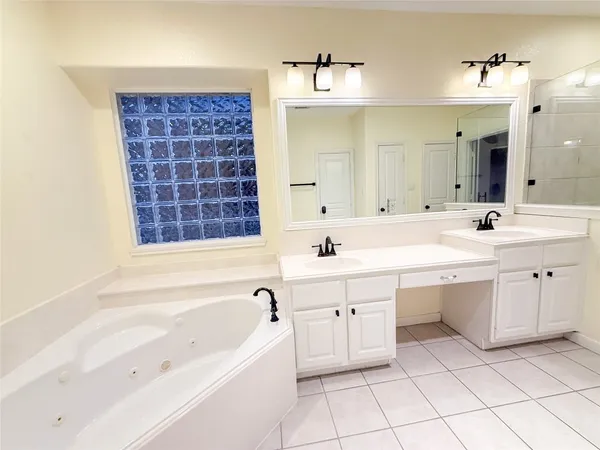 a spacious bathroom with a double vanity sink mirror and bathtub