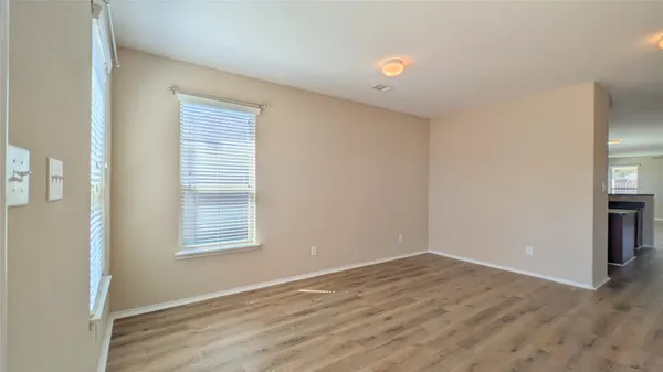 a view of an empty room with wooden floor and a window