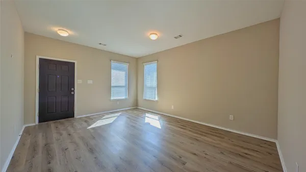 a view of an empty room with wooden floor and closet