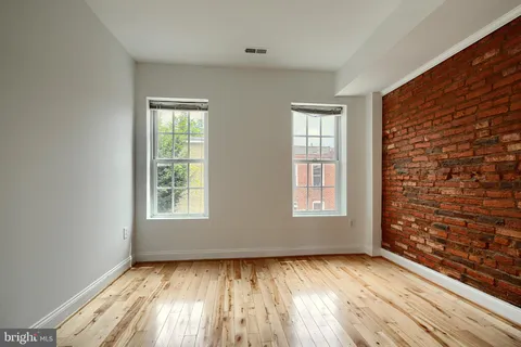 a view of a hallway with wooden floor and a bathroom