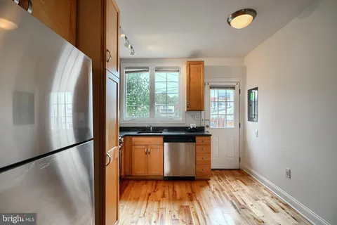 a kitchen with stainless steel appliances a refrigerator sink and wooden floor