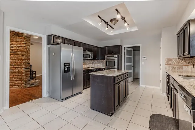 a kitchen with stainless steel appliances granite countertop a refrigerator and a stove top oven