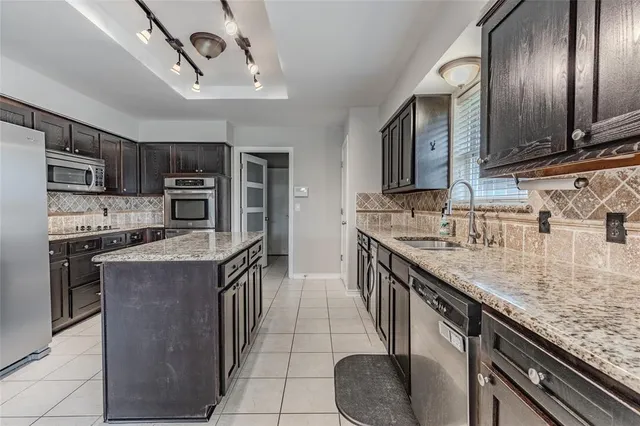a kitchen with stainless steel appliances granite countertop a sink dishwasher stove and refrigerator