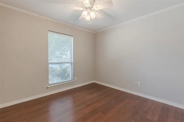an empty room with wooden floor chandelier fan and windows