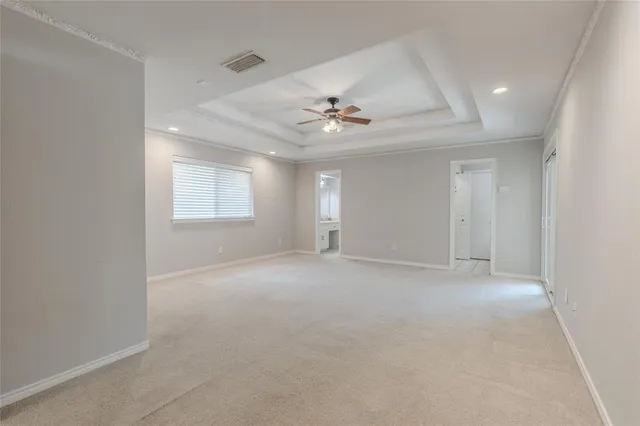 an empty room with chandelier fan and windows