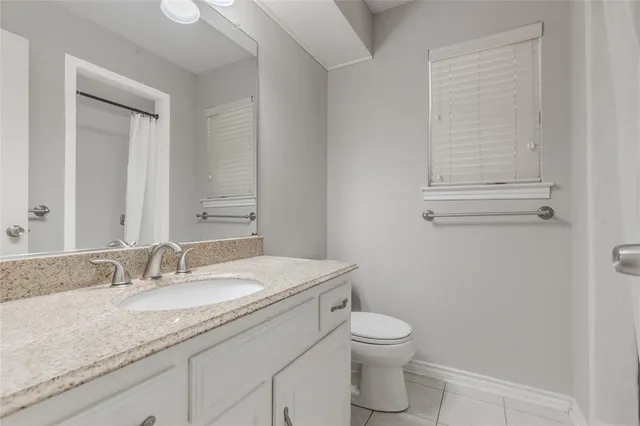 a bathroom with a granite countertop toilet a sink and a mirror