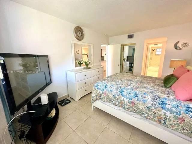 a bedroom with a bed and a flat tv screen on dresser