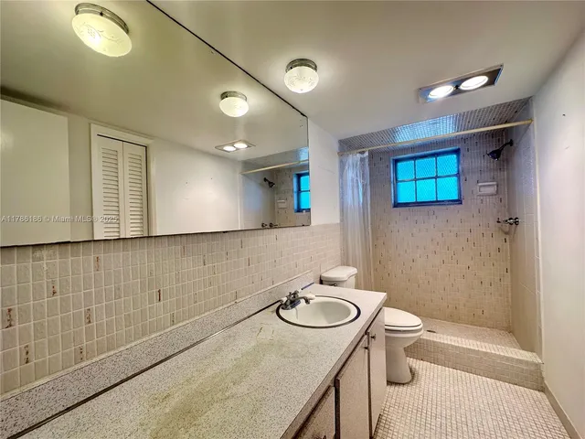 a bathroom with a granite countertop sink a toilet a mirror and shower