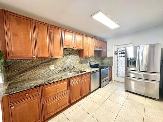 a kitchen with stainless steel appliances granite countertop a sink stove refrigerator and cabinets