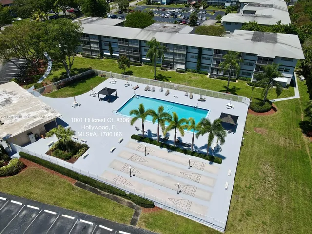 an aerial view of a tennis ground and a cars park side of the road