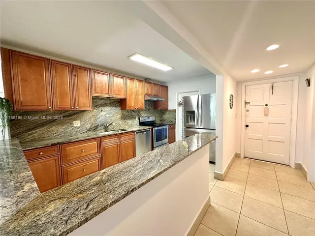 a large kitchen with kitchen island granite countertop a large counter top stainless steel appliances and cabinets