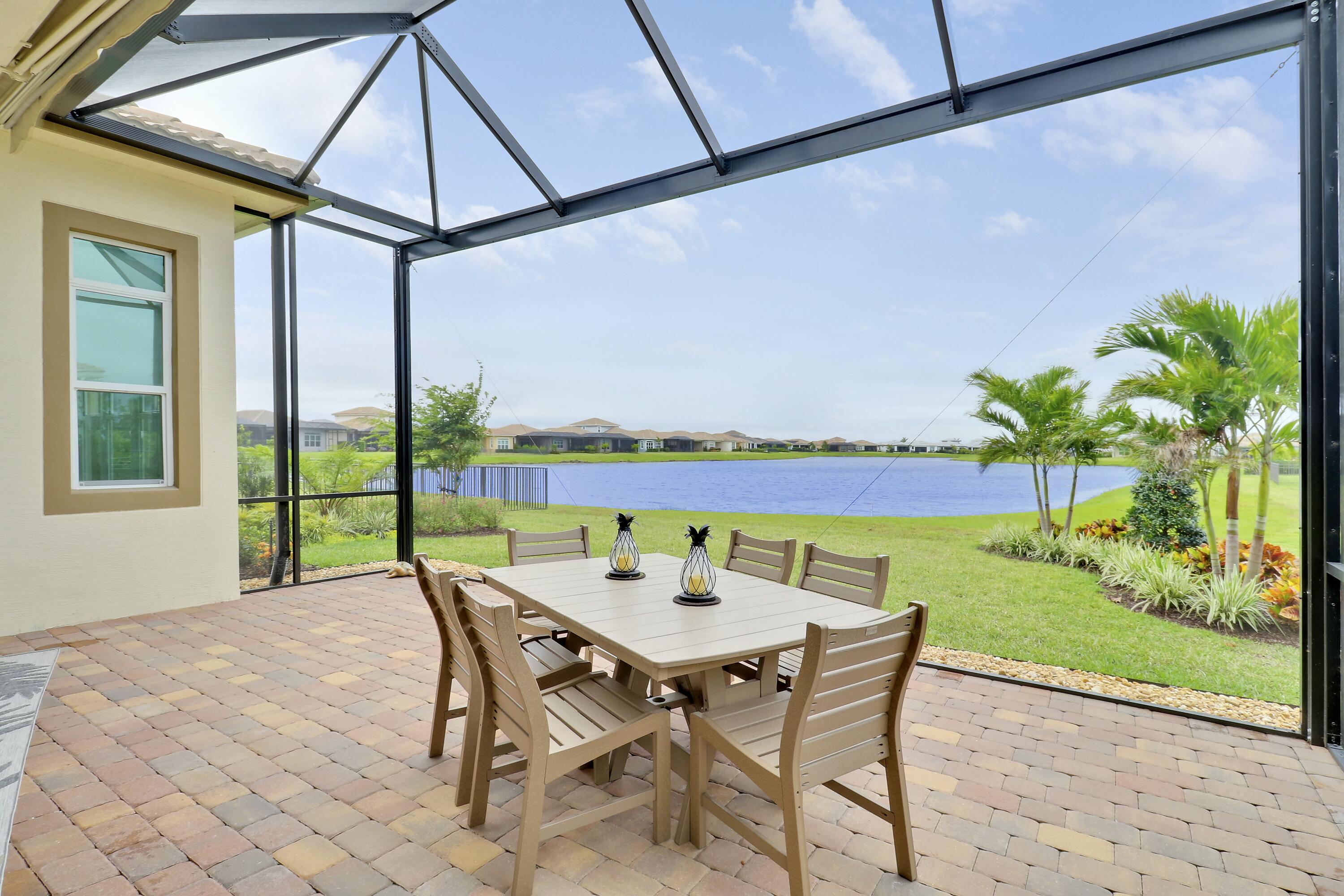 9182 Southwest Pepoli Way Port St. Lucie, FL 34987 - Photo 1 of 80 a view of a patio with a table and chairs under an umbrella