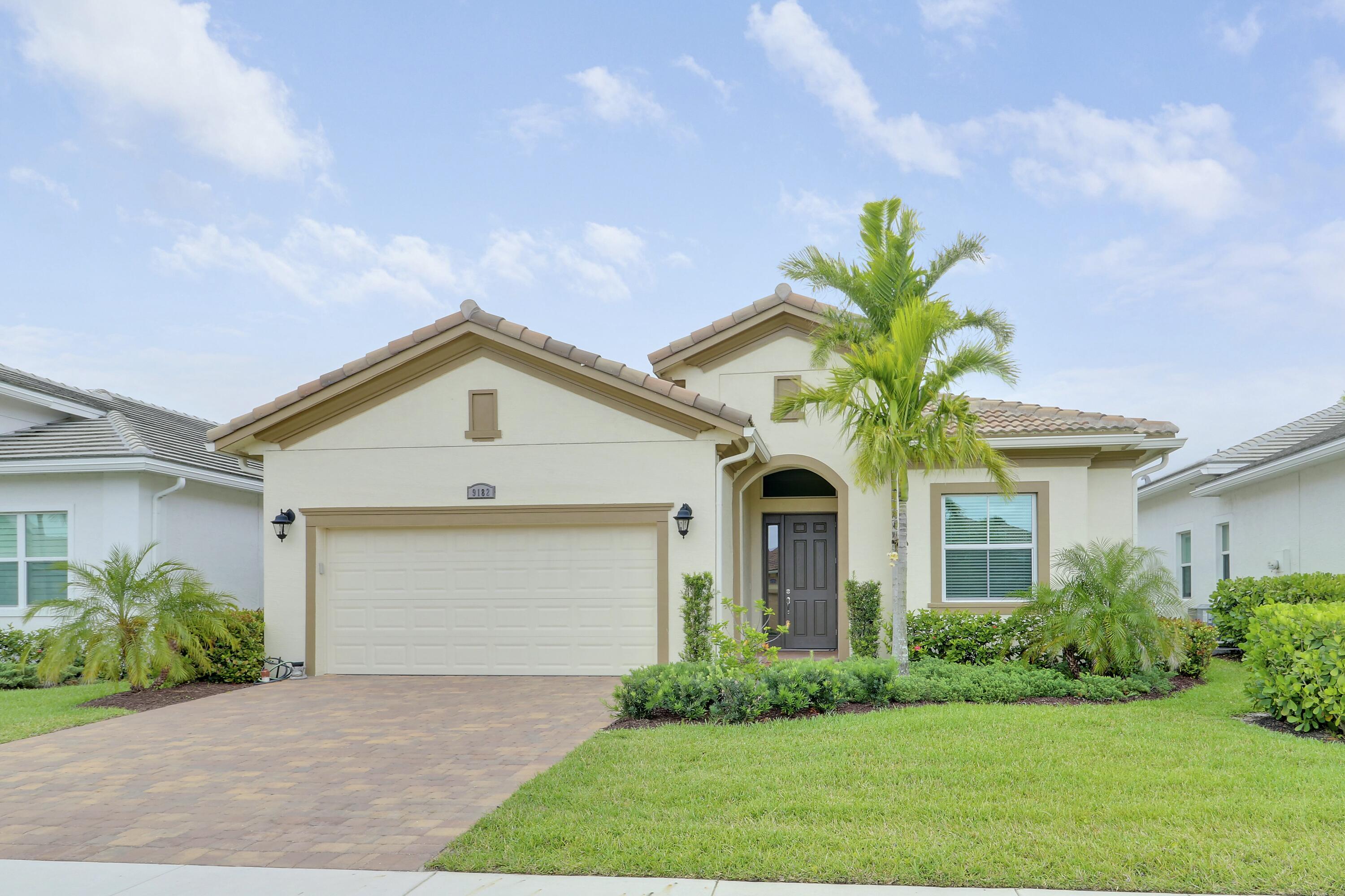 9182 Southwest Pepoli Way Port St. Lucie, FL 34987 - Photo 2 of 80 a front view of a house with a garden and plants