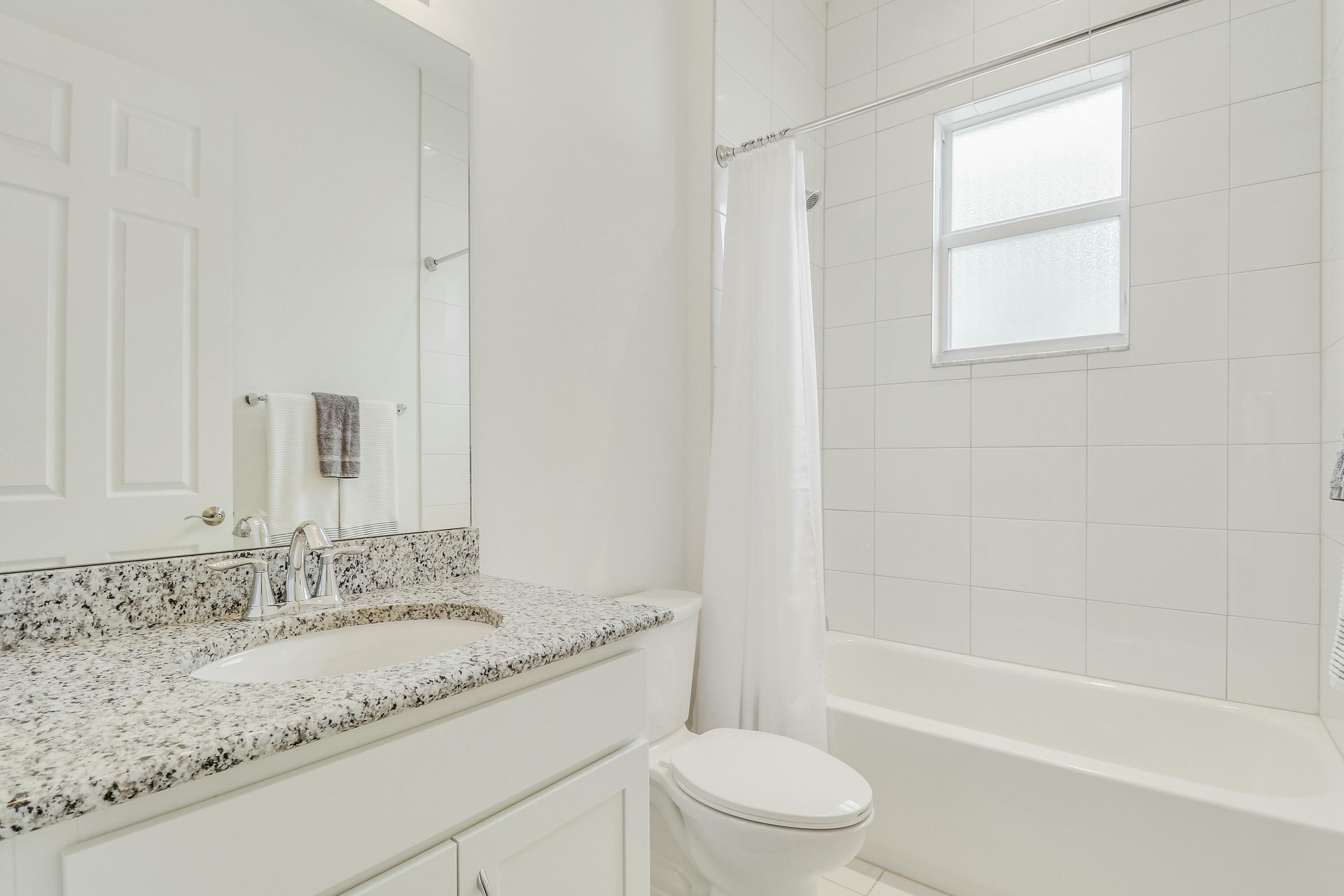 9182 Southwest Pepoli Way Port St. Lucie, FL 34987 - Photo 29 of 80 a bathroom with a granite countertop sink a toilet and bathtub