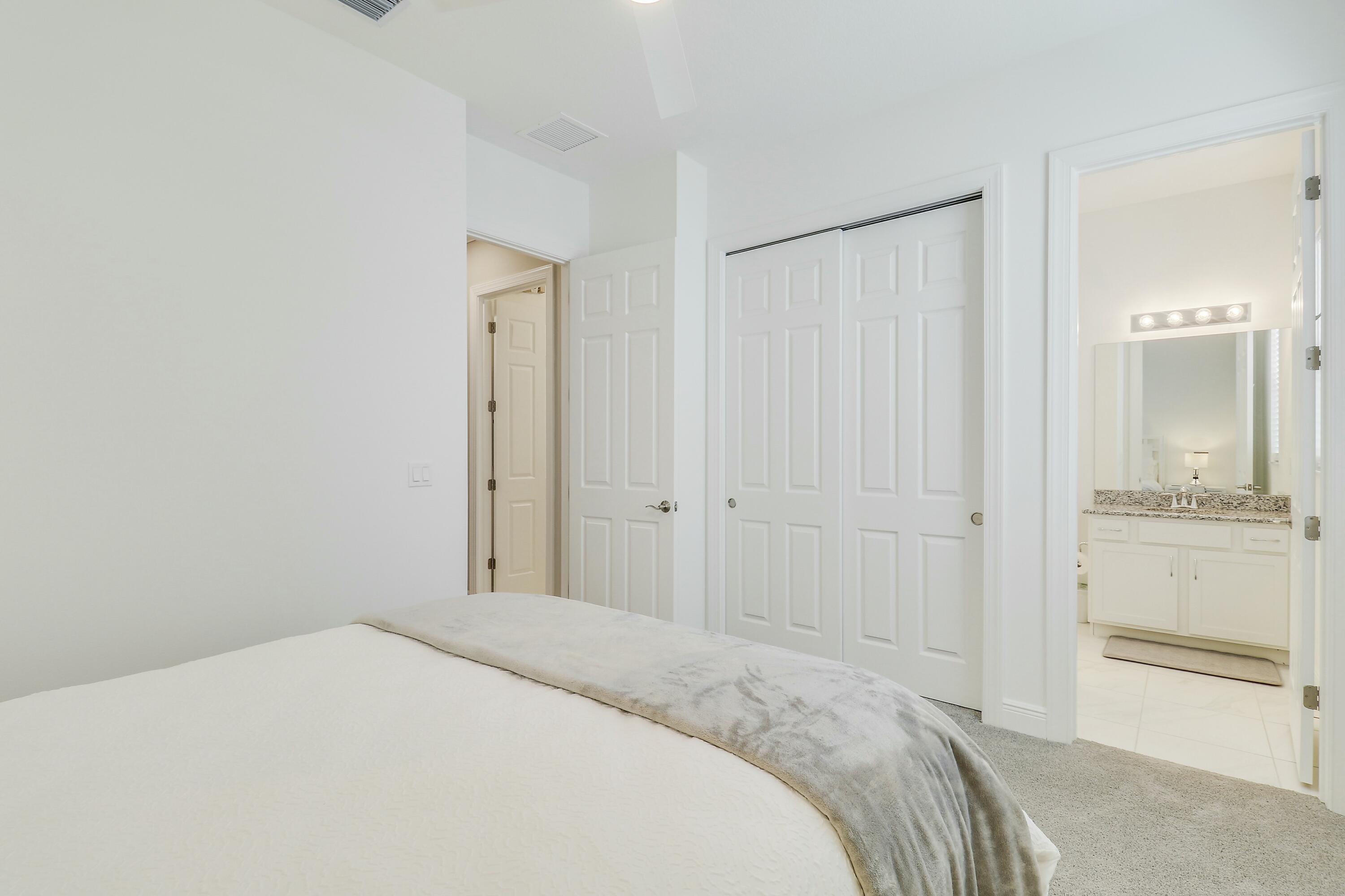 9182 Southwest Pepoli Way Port St. Lucie, FL 34987 - Photo 32 of 80 a bedroom with a bed and a bathroom with sink