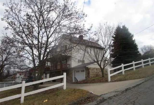 a view of wooden house with large trees