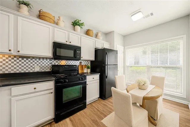 a kitchen with stainless steel appliances a stove a sink dishwasher a refrigerator white cabinets and wooden floor