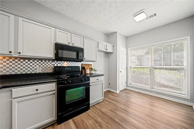 a kitchen with granite countertop a stove and a wooden floors
