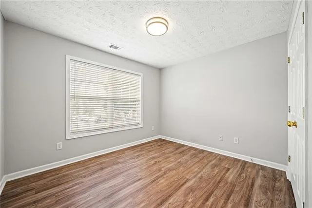 an empty room with wooden floor and window