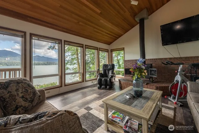 a living room with furniture a flat screen tv and floor to ceiling window