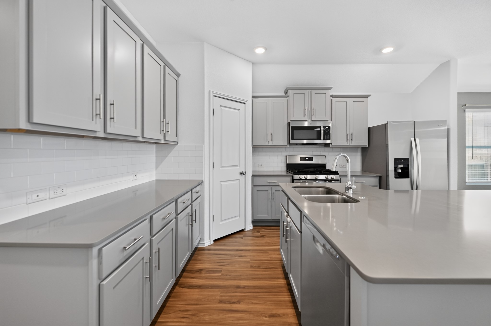128 Konik Road Georgetown, TX 78626 - Photo 7 of 34 Sleek, modern kitchen features abundant gray cabinetry, durable countertops, and warm wood flooring.