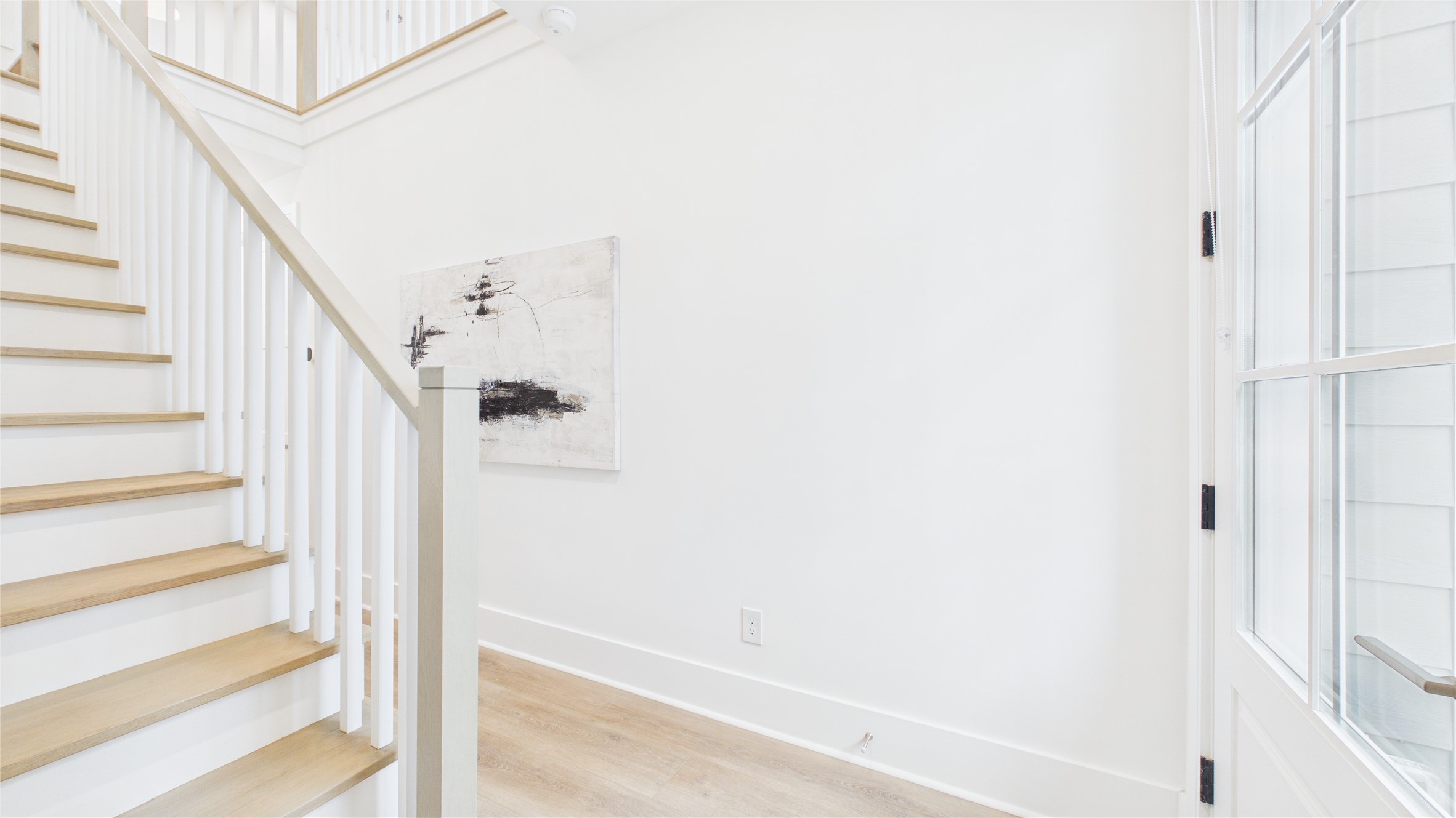 602 Skyland Terrace Way Houston, TX 77009 - Photo 35 of 40 Bright and airy entryway with light wood flooring and stairs, white walls, and a large windowed door. The space features contemporary decor and a clean, modern aesthetic.
