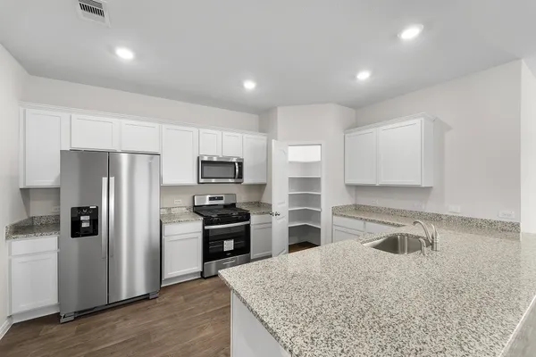 a kitchen with kitchen island granite countertop a sink stove and refrigerator
