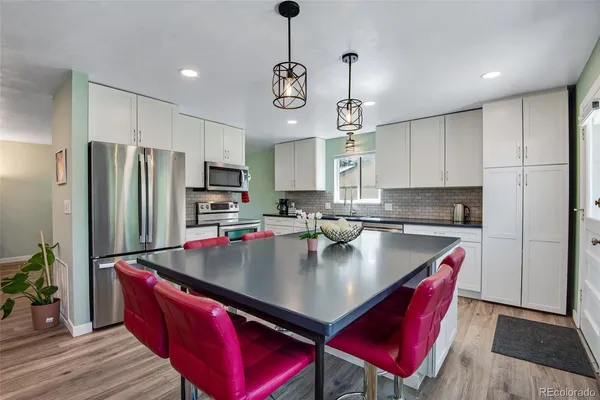 a kitchen with stainless steel appliances granite countertop a sink a stove a refrigerator cabinets and wooden floor