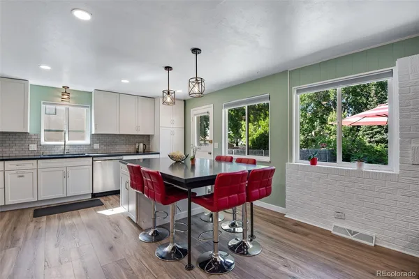 a kitchen with granite countertop a stove a sink dishwasher a dining table and chairs with wooden floor