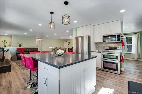 a kitchen with kitchen island a sink appliances and wooden floor