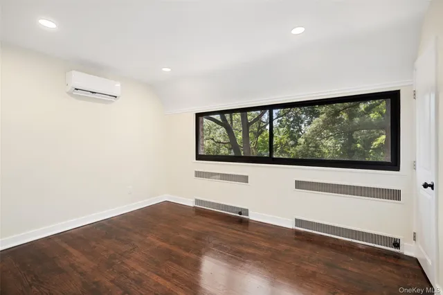 a view of an empty room with wooden floor and windows