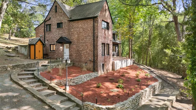 a view of a brick house with large windows and a tree