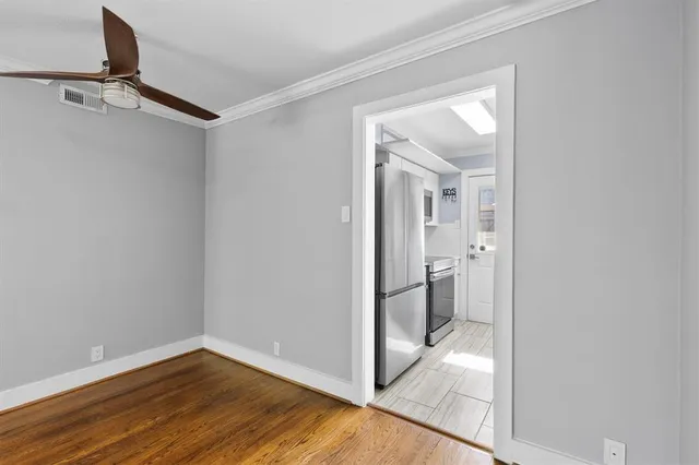 a view of a hallway with wooden floor and a bathroom