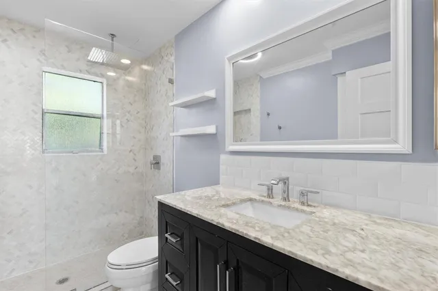 a bathroom with a granite countertop sink a toilet and a mirror