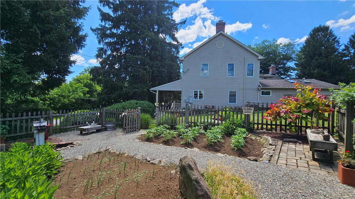 585 Buttermilk Road Hellertown, PA 18055 - Photo 55 of 82 A quaint backyard garden with raised beds and a stone path leading to a charming picket fence.